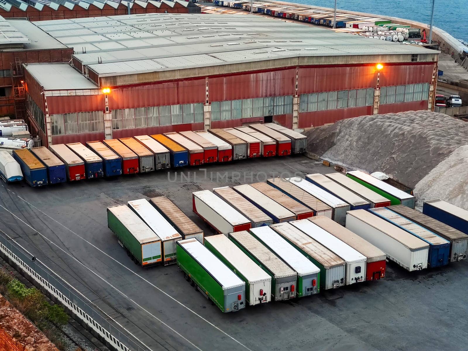 Commercial port with parked cargo prepared for the worldwide transportation of raw commodities, logistics, and global industry