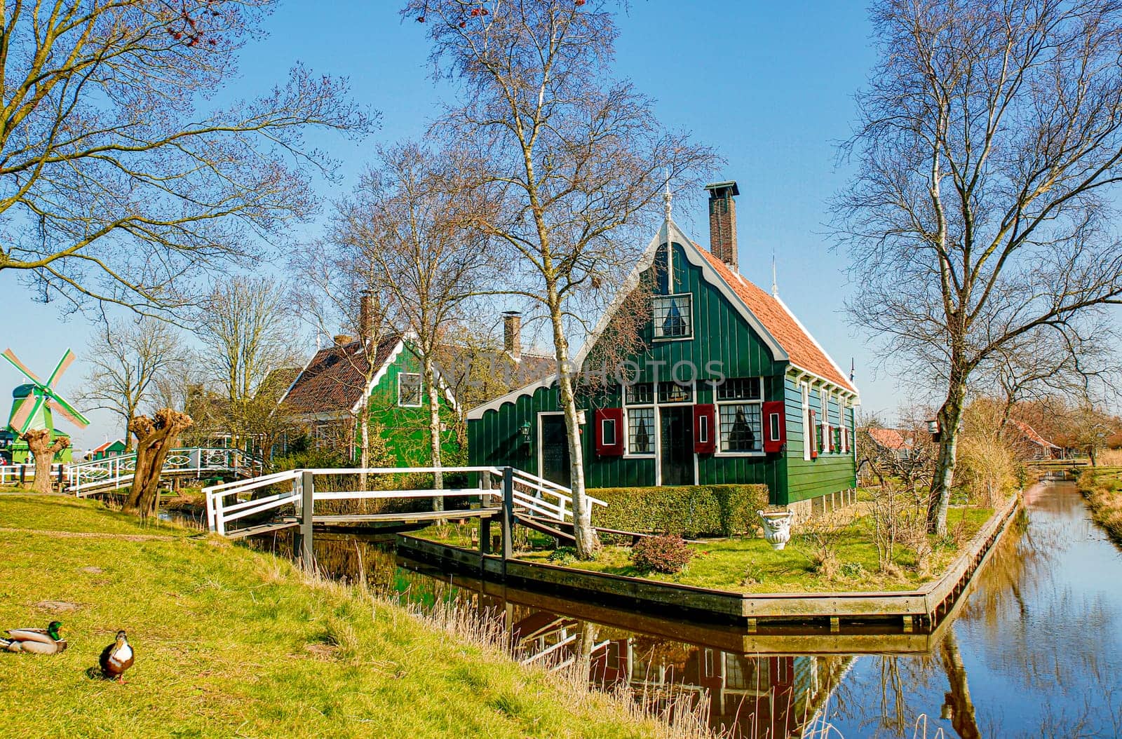 Typical Dutch scenery with a historic home on a lake and an antique windmill in the background