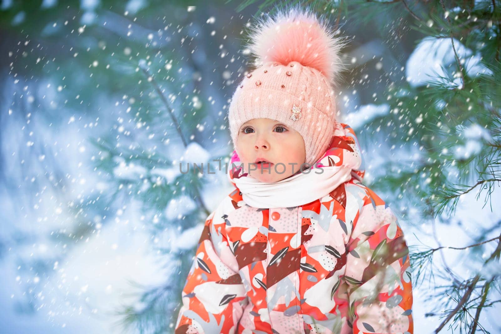 Beautiful little girl in winter clothes on the background of snowy nature. Child on a winter walk.