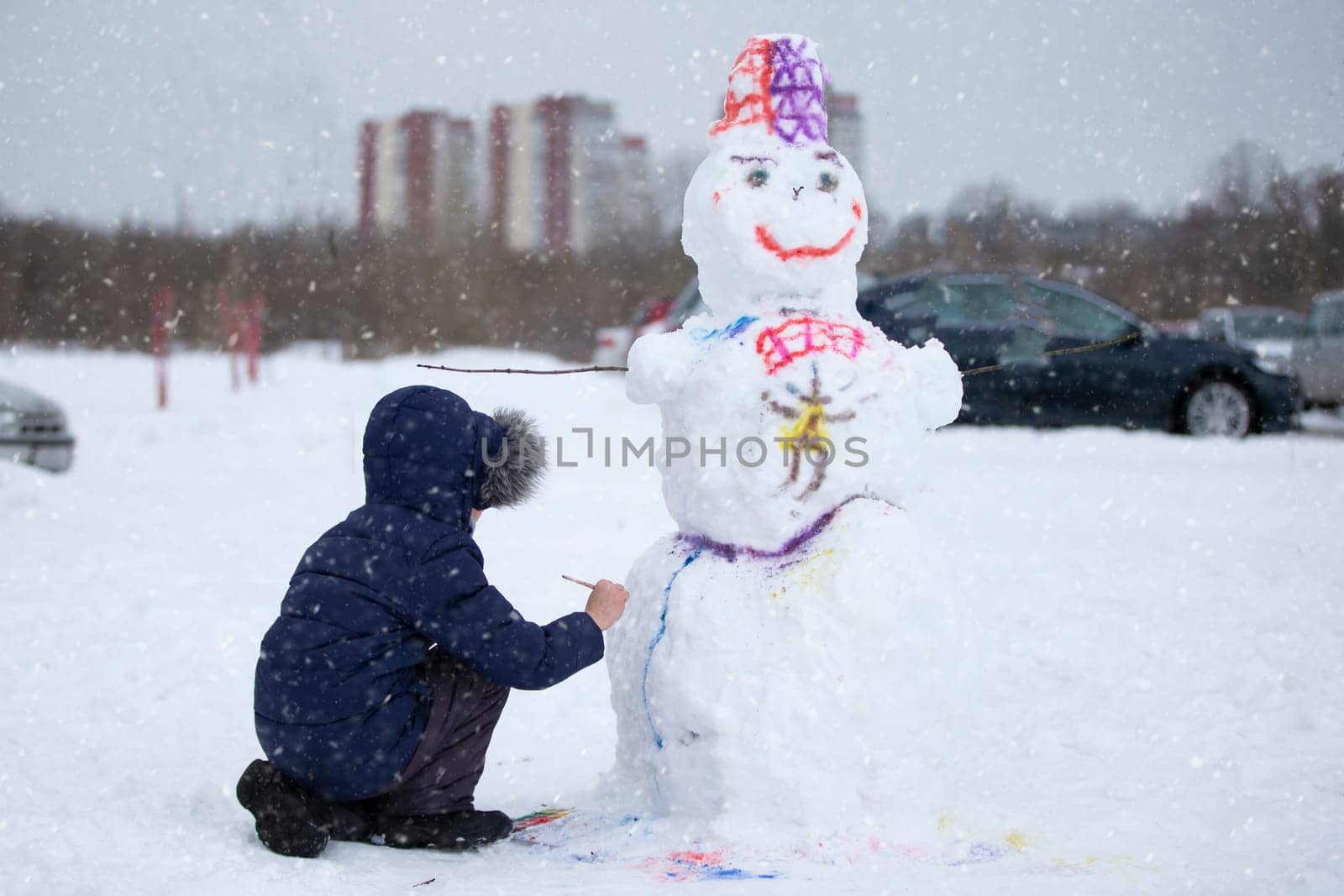 A boy paints a snowman on a winter day.