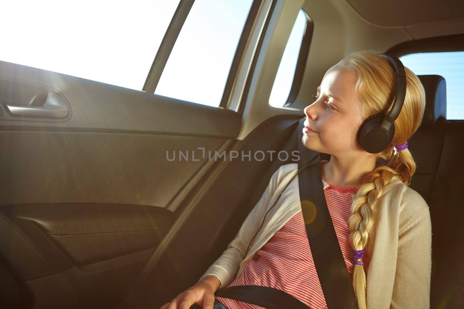 Listening to her favorite travel songs. a little girl traveling in a car
