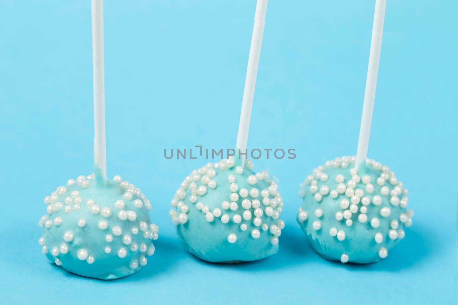 Candies on sticks. Blue cakes on a blue background.Beautiful sweet dessert by Sviatlana