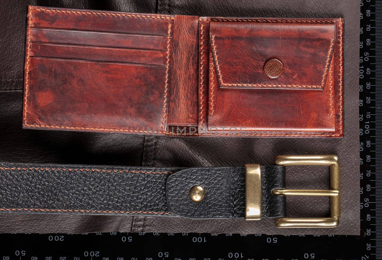 Leather goods purse and belt against the background of a ruler for cutting and sewing.