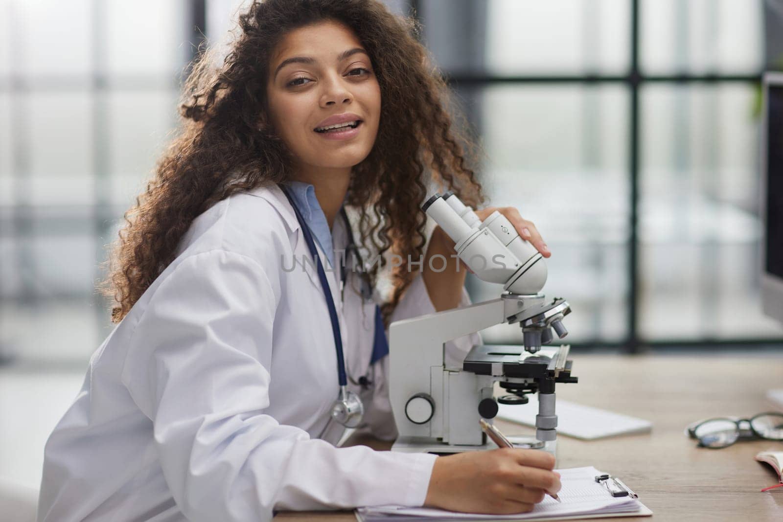 Attractive female scientist looking through a microscope