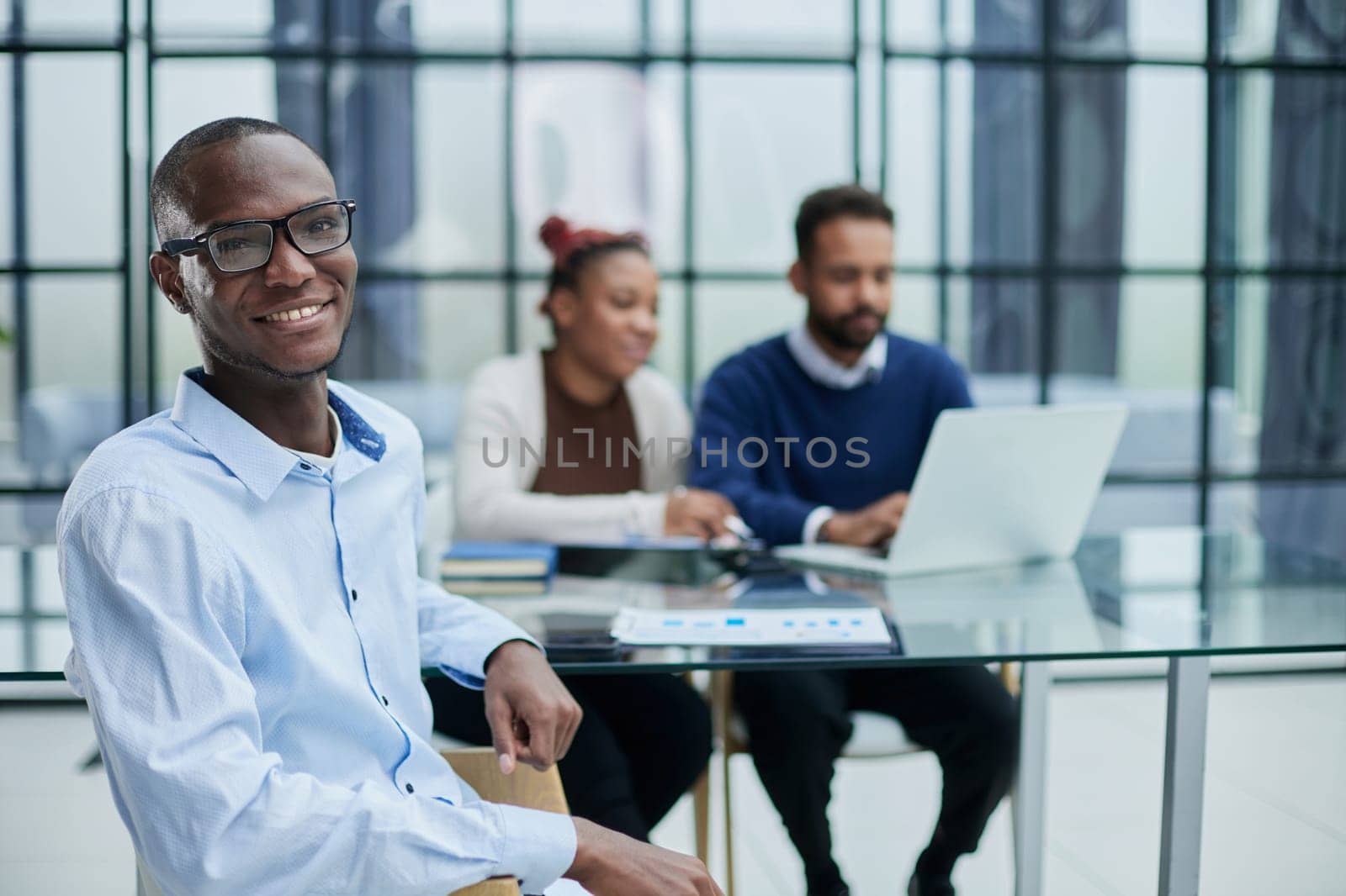 An African-American student sits on a chair in a room.