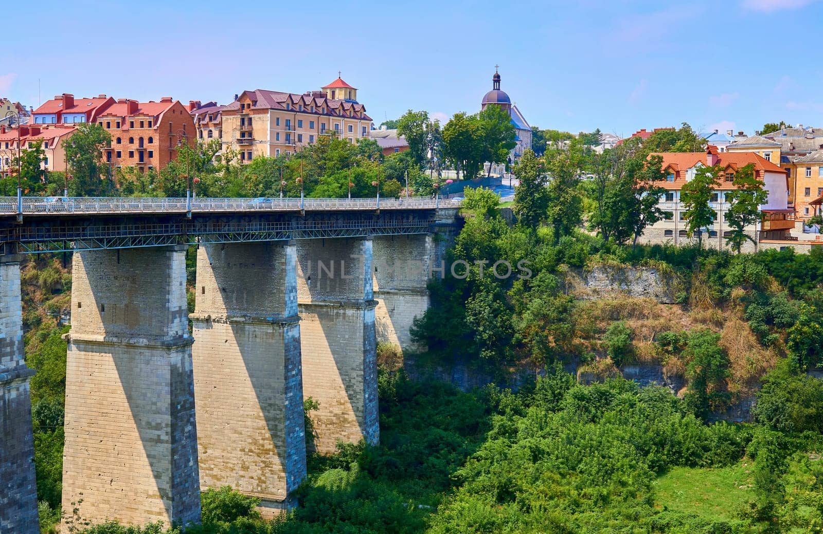 a structure carrying a road, path, railroad, or canal across a river, ravine, road, railroad, or other obstacle. High bridge over a canyon in a summer medieval town.