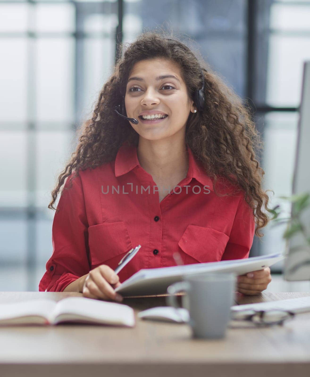 Attractive young business woman, writing notes to notebook at her workplace in office.