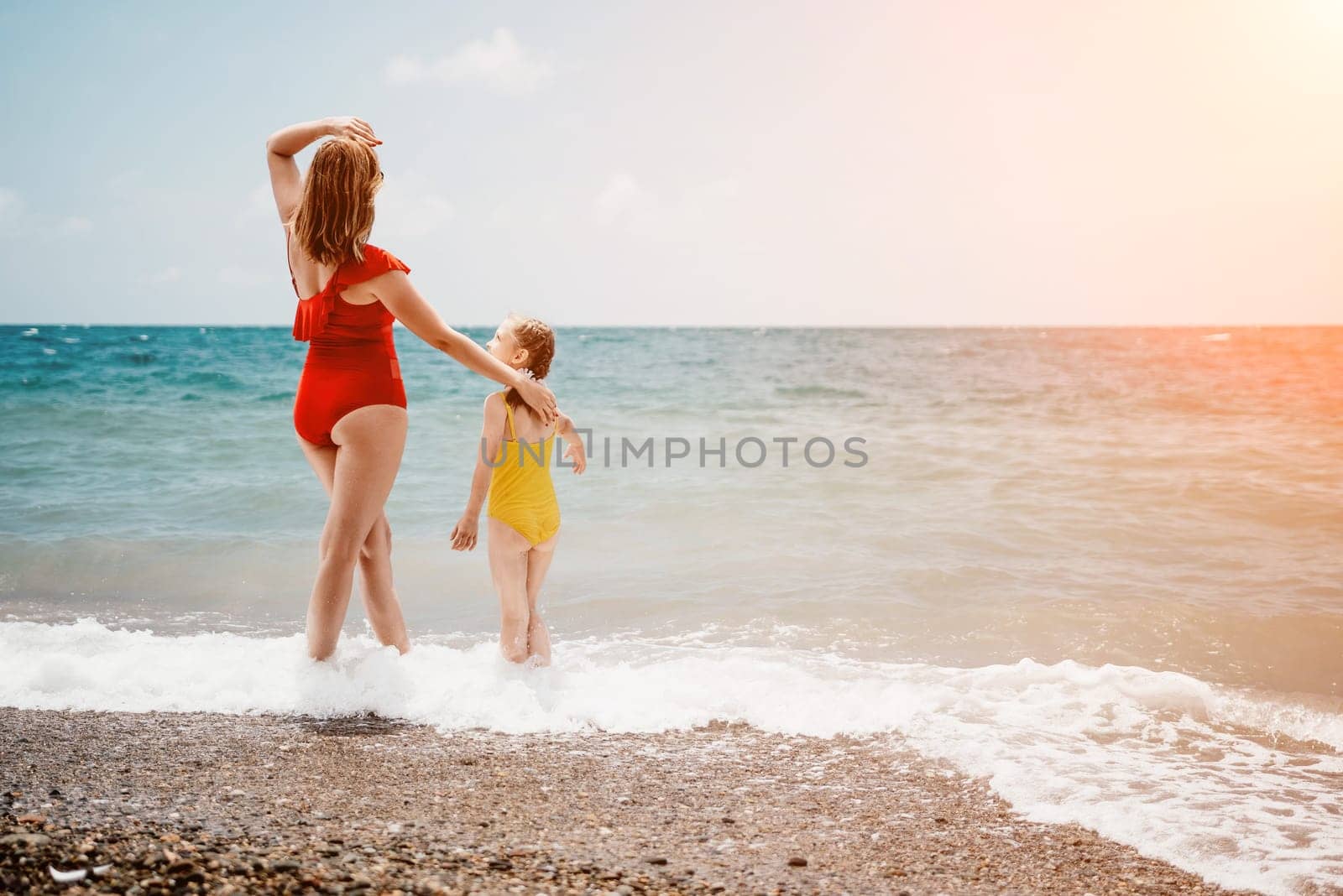Happy loving family mother and daughter having fun together on the beach. Mum playing with her kid in holiday vacation next to the ocean - Family lifestyle and love concept.