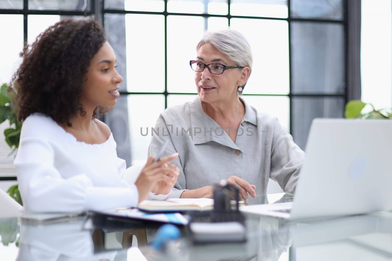 Female colleagues of different nationalities and ages met in the office hall discussing work issues