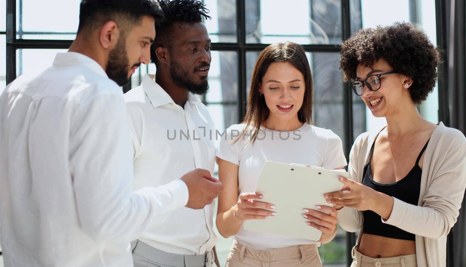 Happy young female employee discussing online project, showing computer presentation to skilled team leader in eyeglasses. Friendly diverse colleagues working in pairs on laptop, using applications.