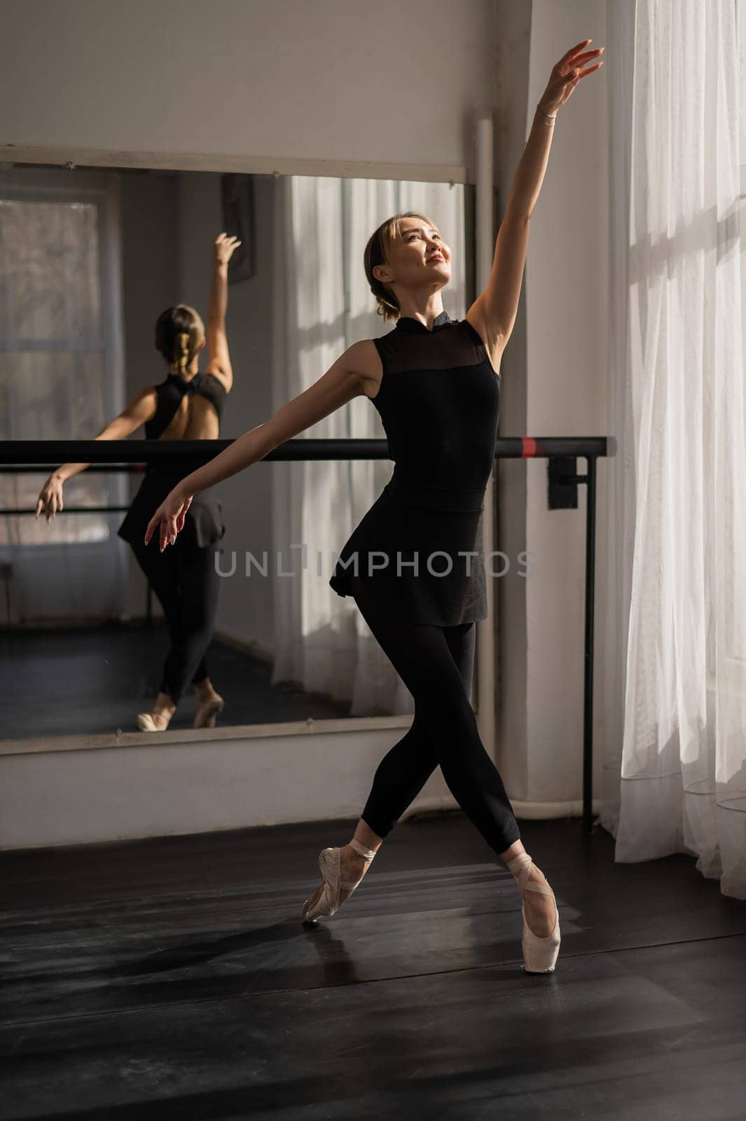 A beautiful Asian ballerina is training in a dance class. Vertical photo