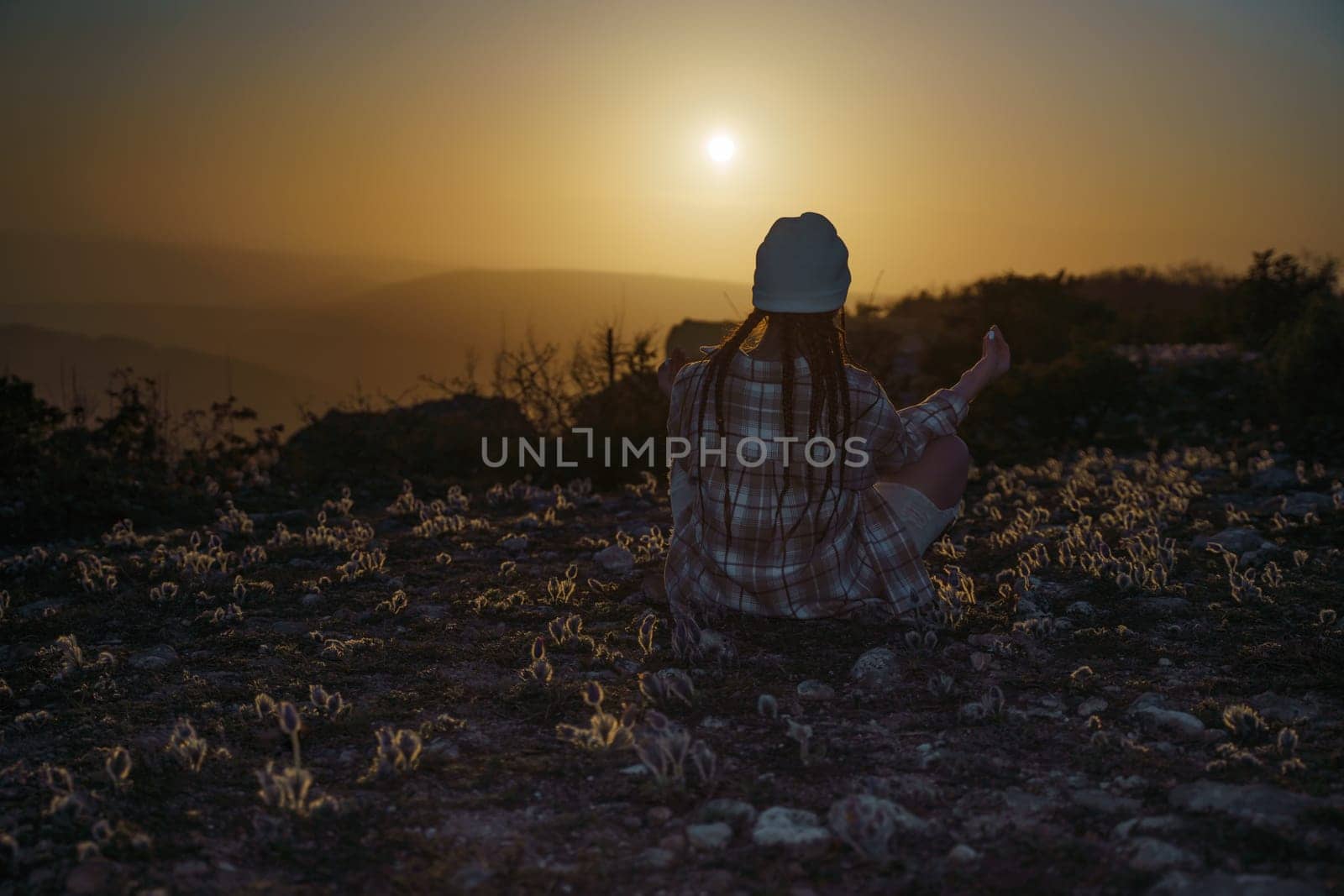 Woman tourist on top of sunrise mountain. The girl salutes the sun, wearing a jacket, white hat and white jeans. Conceptual design