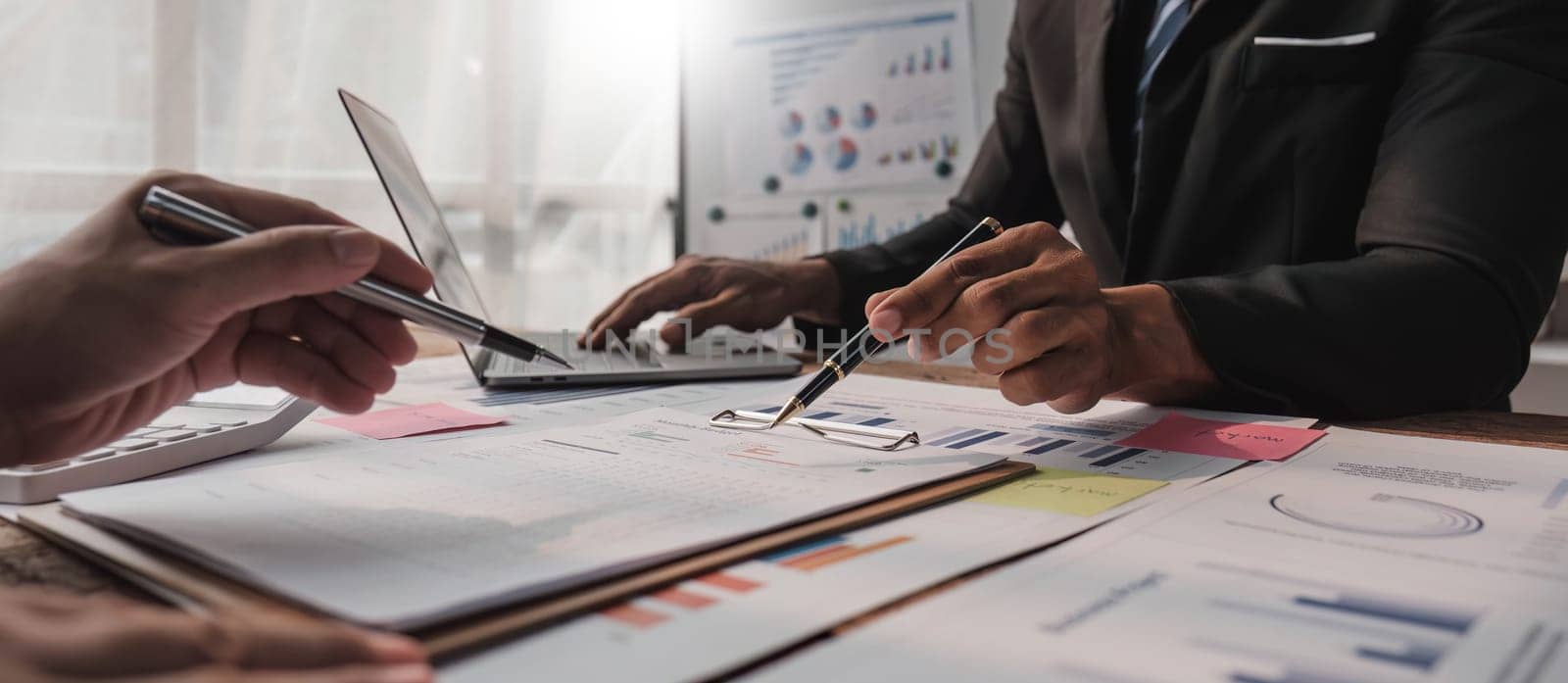 Two business people talk project strategy at office meeting room. Businessman discuss project planning with colleague at modern workplace while having conversation and advice on financial data report by wichayada