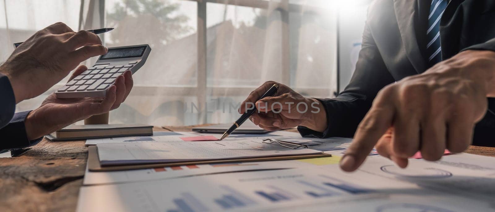 Two business people talk project strategy at office meeting room. Businessman discuss project planning with colleague at modern workplace while having conversation and advice on financial data report by wichayada