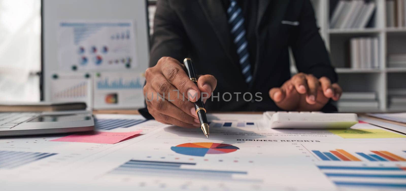 Close up Businessman using calculator and laptop for do math finance on wooden desk in office and business working background, tax, accounting, statistics and analytic research concept. by wichayada