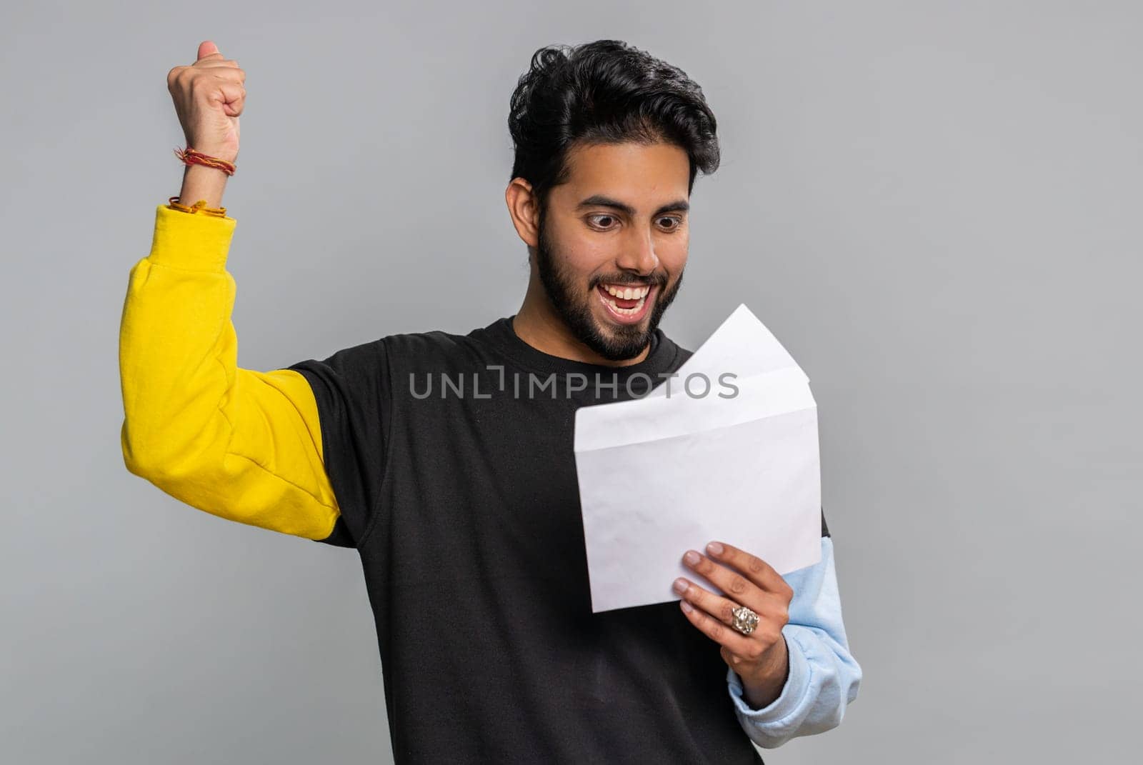 Handsome indian man open envelope take out letter reads it feel happy. Hindu guy career growth advance promotion, bank loan approve, monetary award, long-awaited invitation great news, lottery win