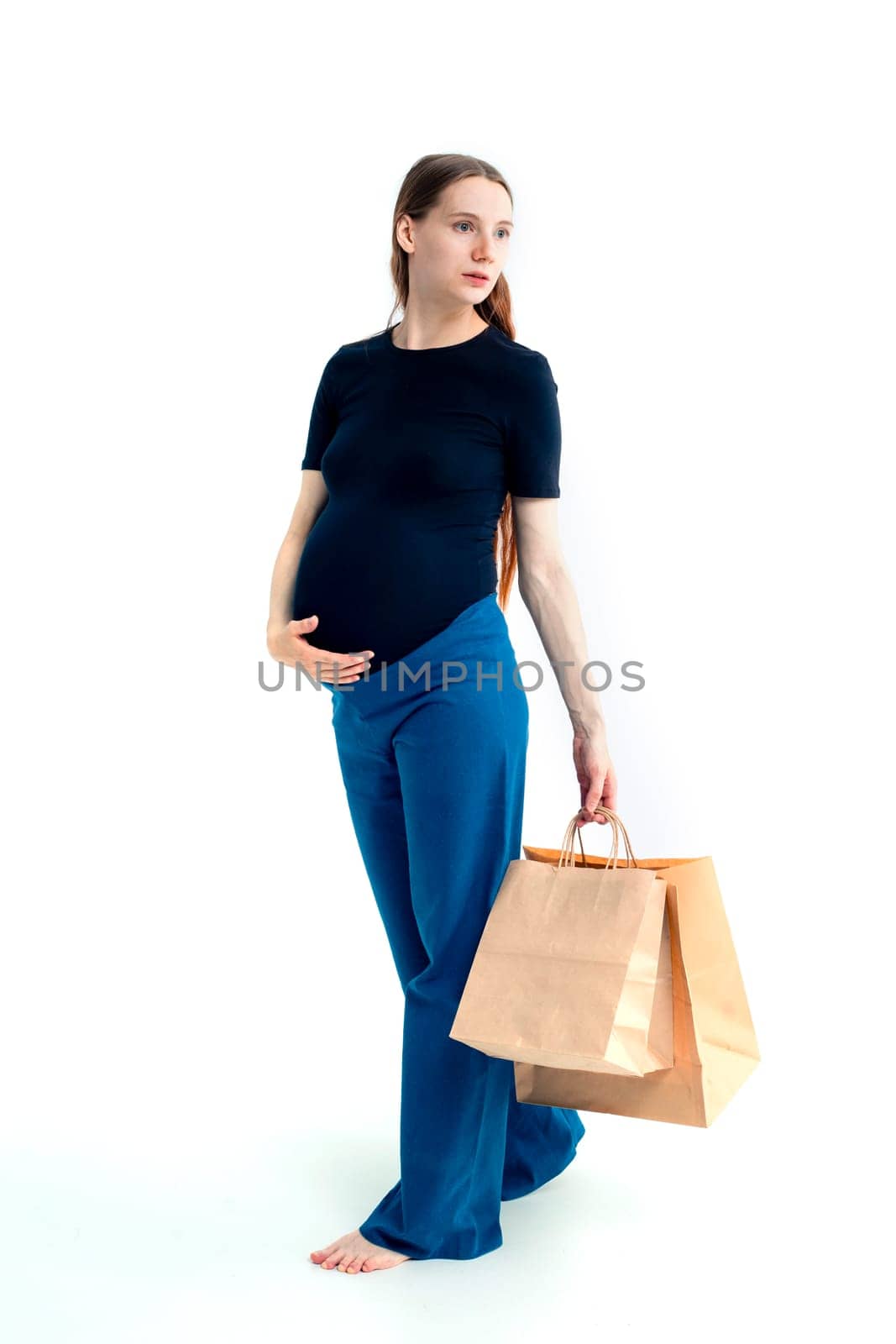 Shopping concept: Young pregnant woman with shopping bags full length portrait on white background.