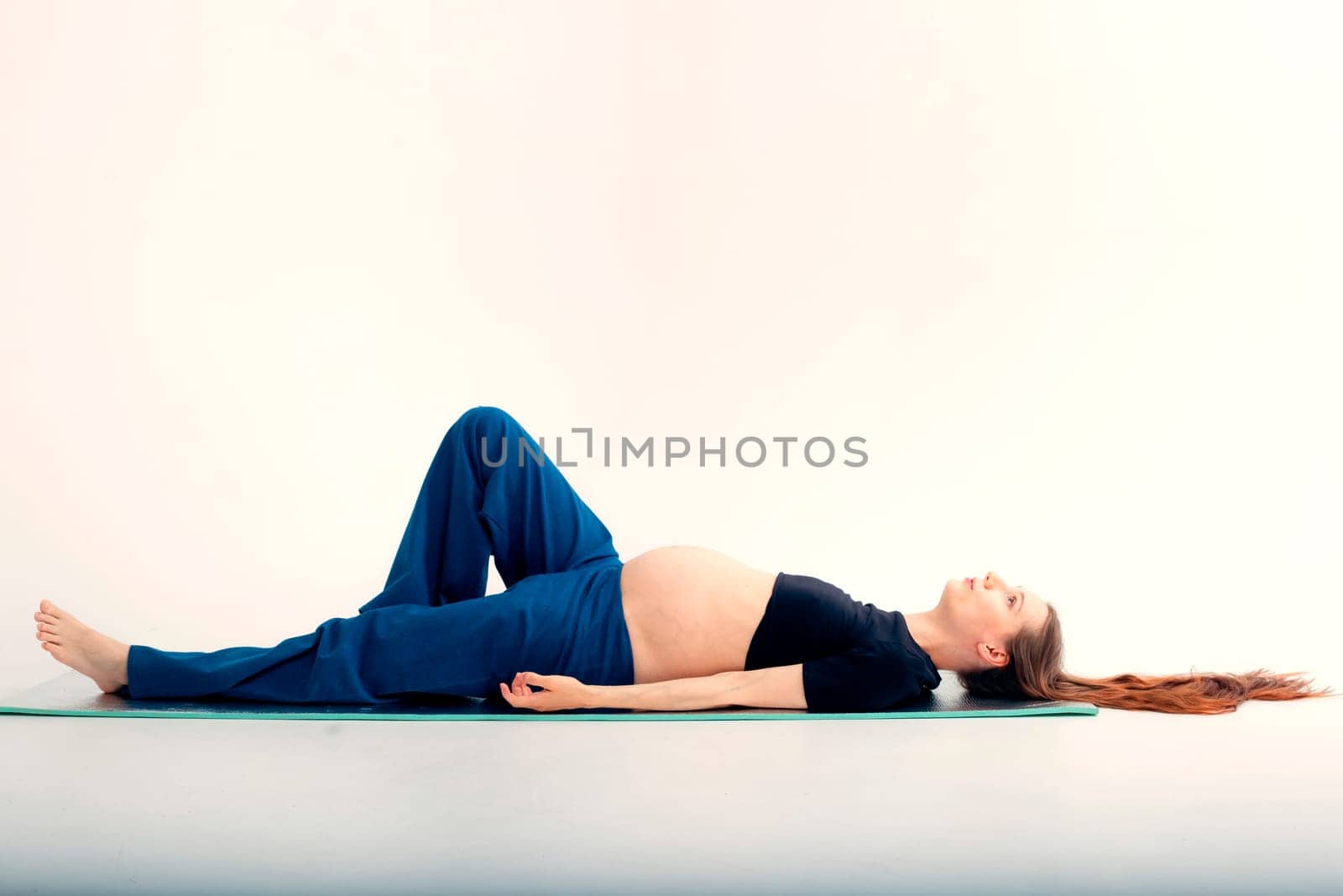 Pleasant pregnant woman posing in profile and trying yoga Young happy expectant relaxing, thinking about her baby and enjoying her future life. Motherhood, pregnancy, yoga concept.