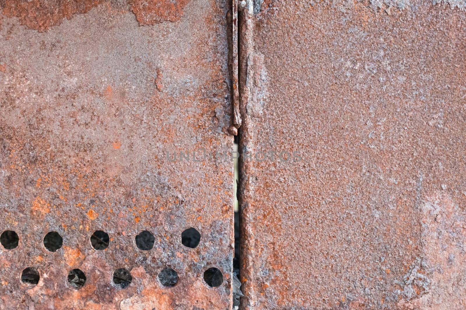 Old rusty grill with round holes pattern brown metal texture steel background.