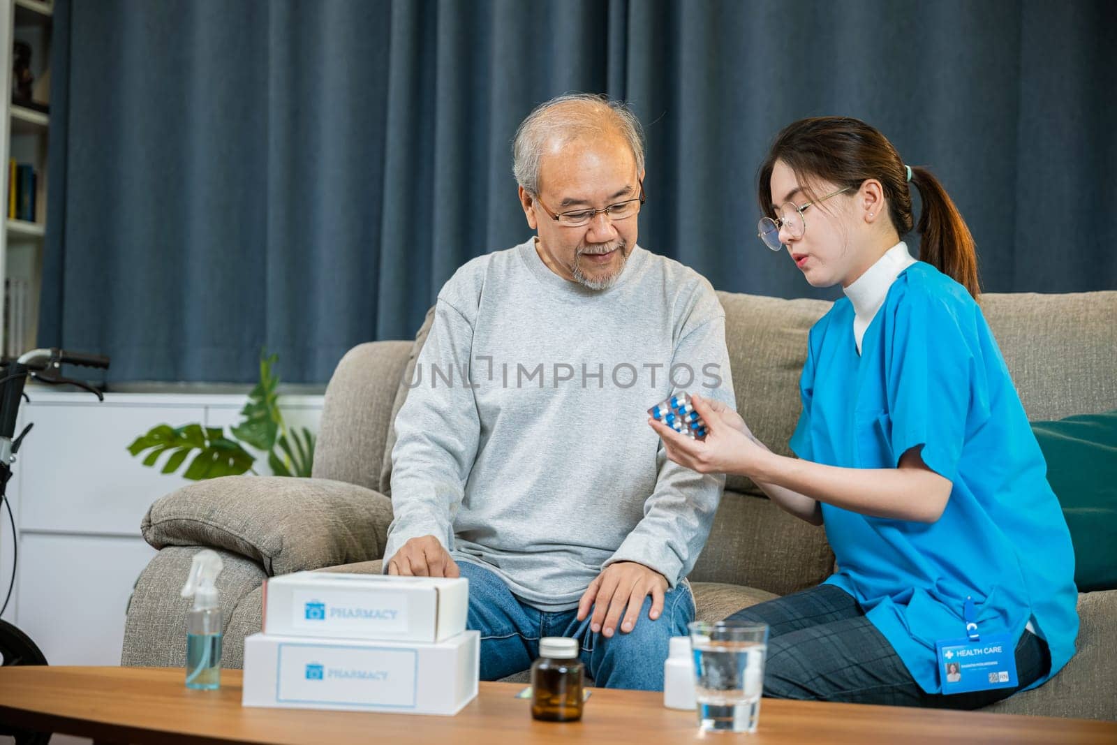 Asian nurse with physician explaining prescription medicine to attentive senior man at home, Doctor woman explain dosage pill old man, Healthcare worker caregiver visiting in house in living room