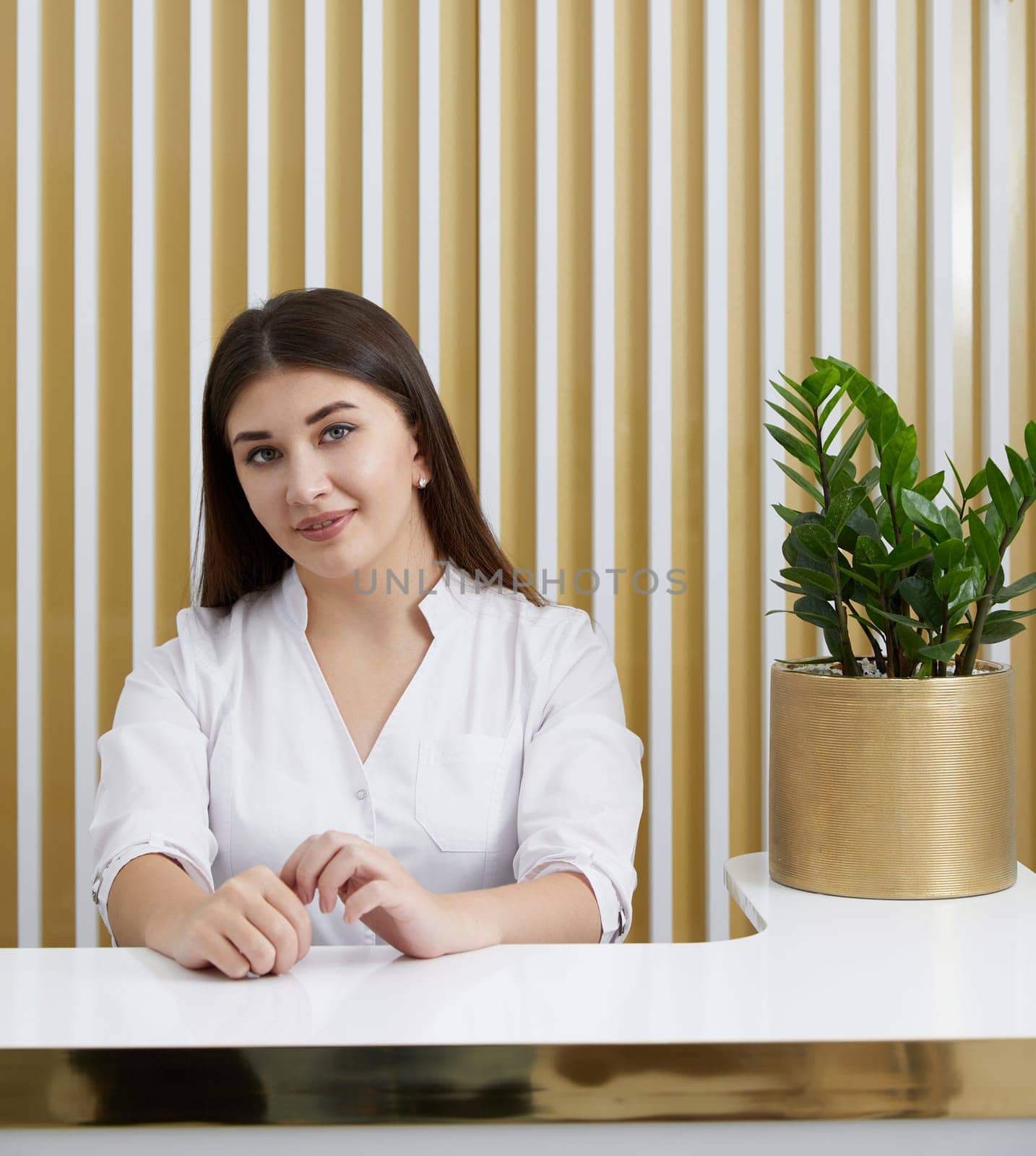 Female receptionist at reception desk in a modern office lobby by Mariakray