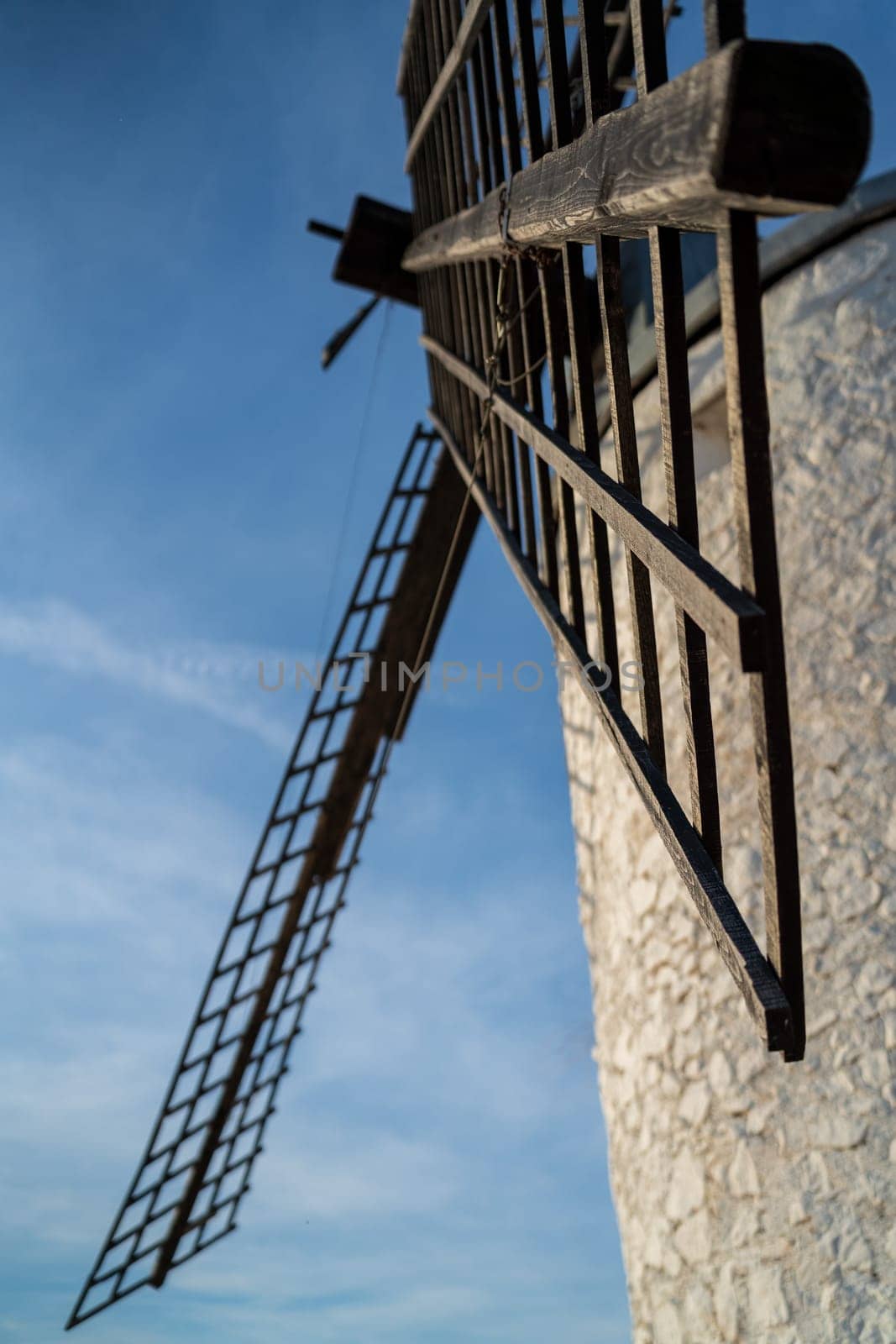 Bottom view of vintage windmill blades against blue sky, vertical composition