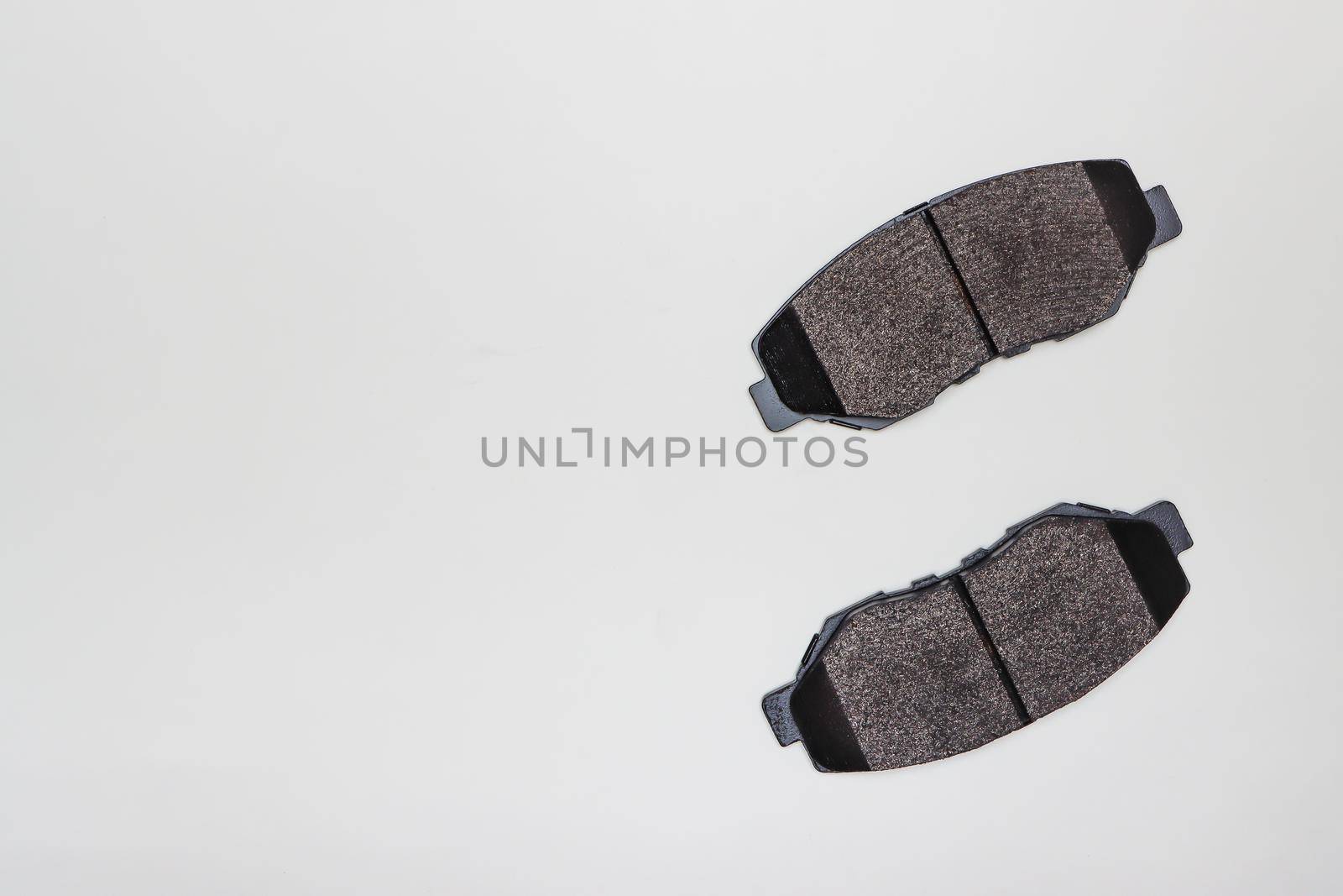 Two brake pads on a flat surface on the side. Set of spare parts for car brake repair. Details on white background, copy space available. UHD 4K.