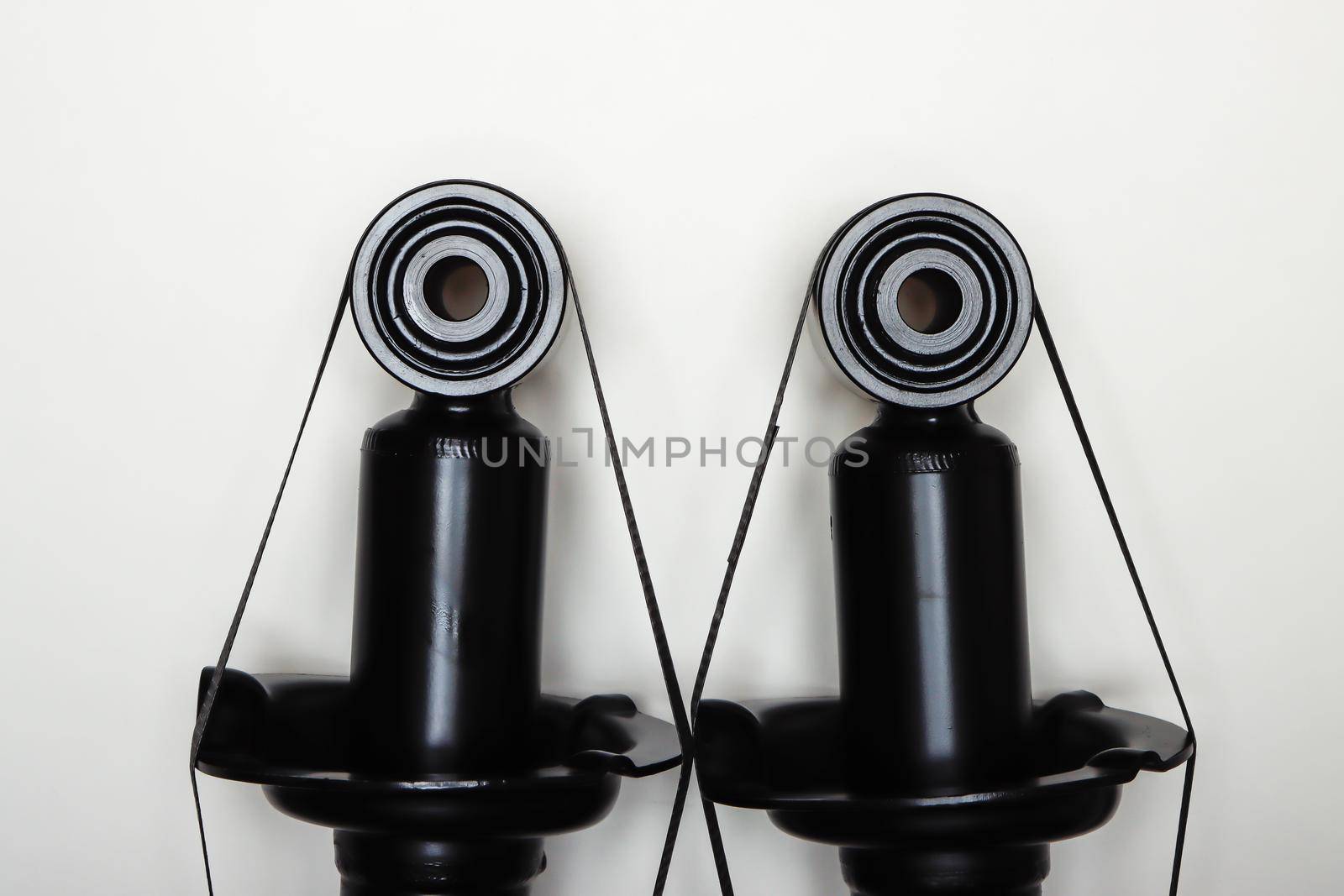 The upper mountings of the shock absorbers for the machine lie on a flat surface. A set of spare parts for the repair of the chassis of the vehicle. Details on white background, copy space available