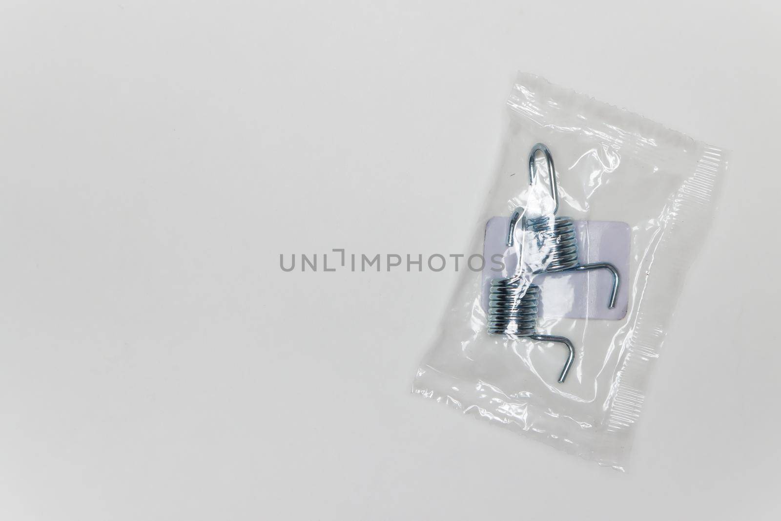 Repair kit for brakes, two metal springs per package. Set of spare parts for car brake repair. Details on white background, copy space available. UHD 4K.