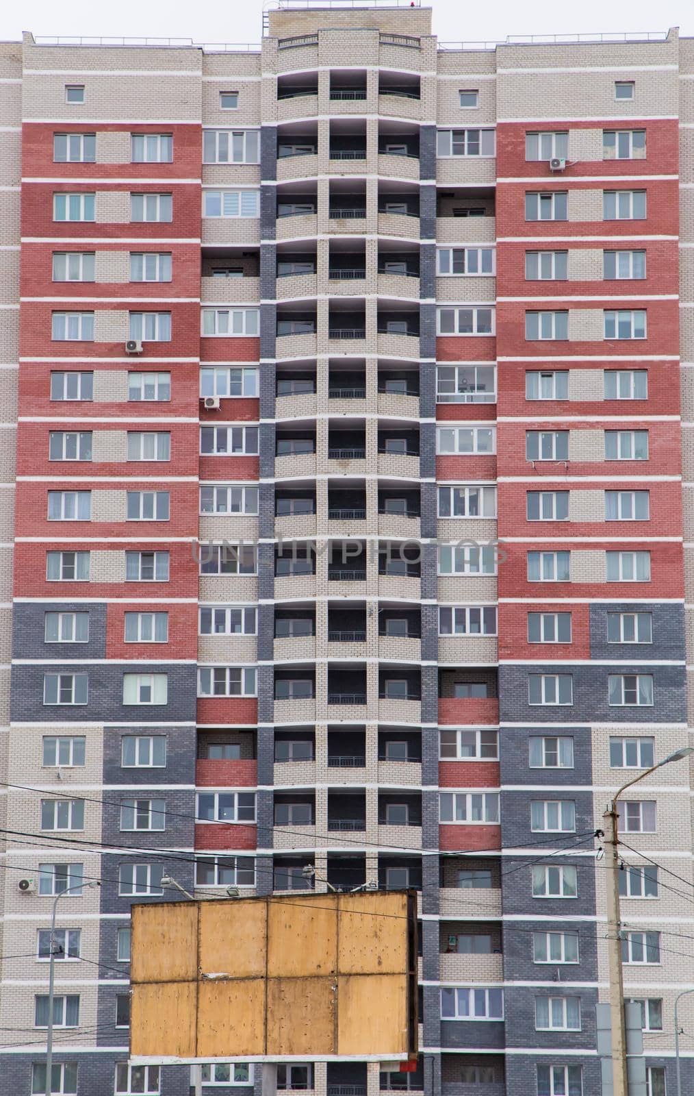 Residential high-rise multi-colored building made of red, gray and white bricks. Modern new buildings, building facades. Real estate and urban architecture concept.