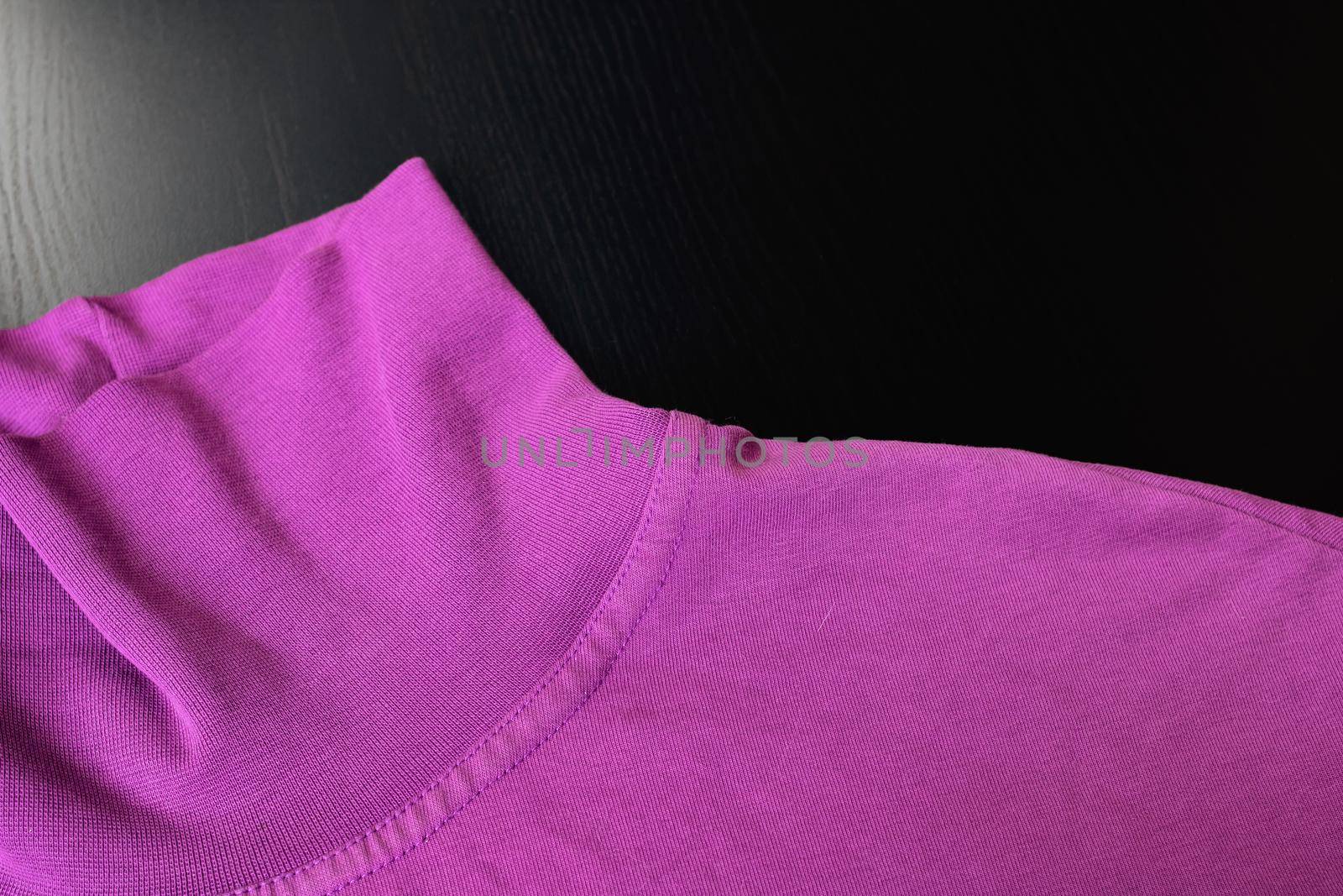 Part of pink sweater on wooden background close up