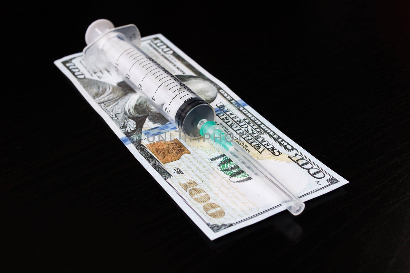 Syringe and dollars on a wooden table close up