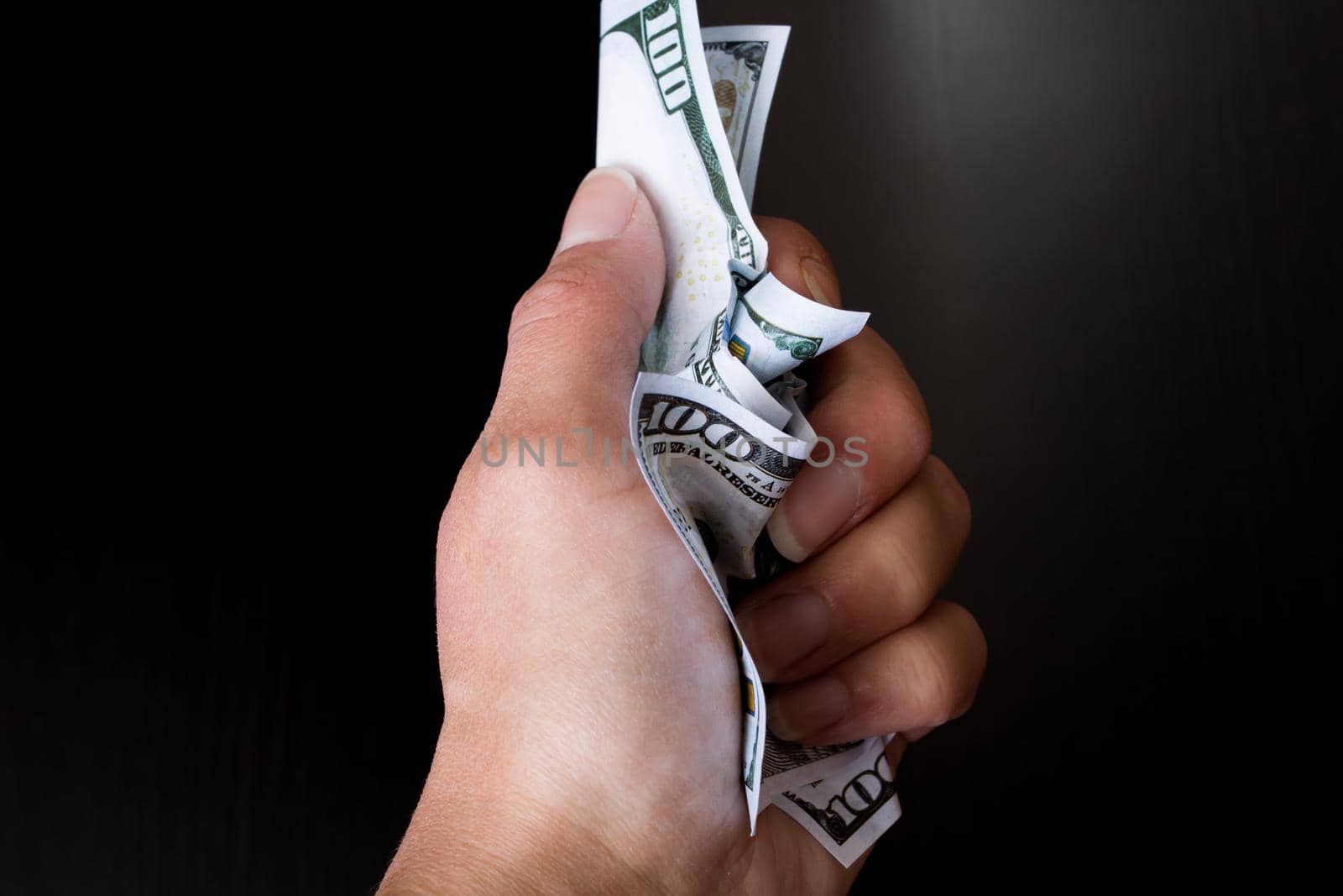 Hand holds rumpled dollars on a wooden background