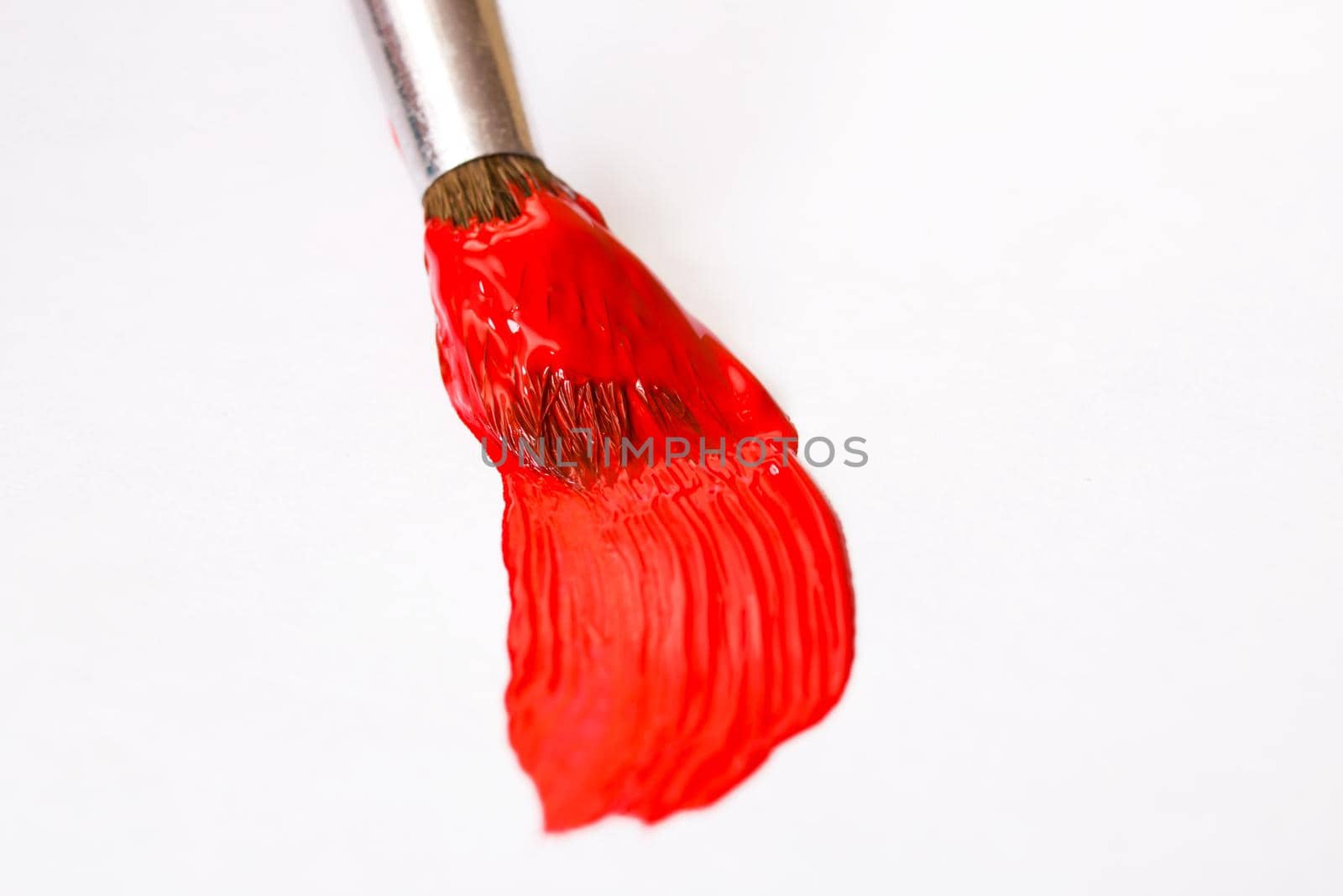 Brush with red paint on a sheet of paper