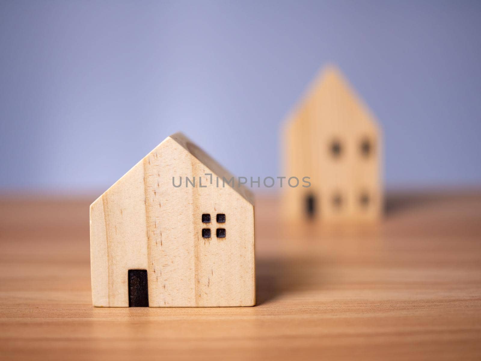 Two wooden model houses placed on a wooden table. with a white background