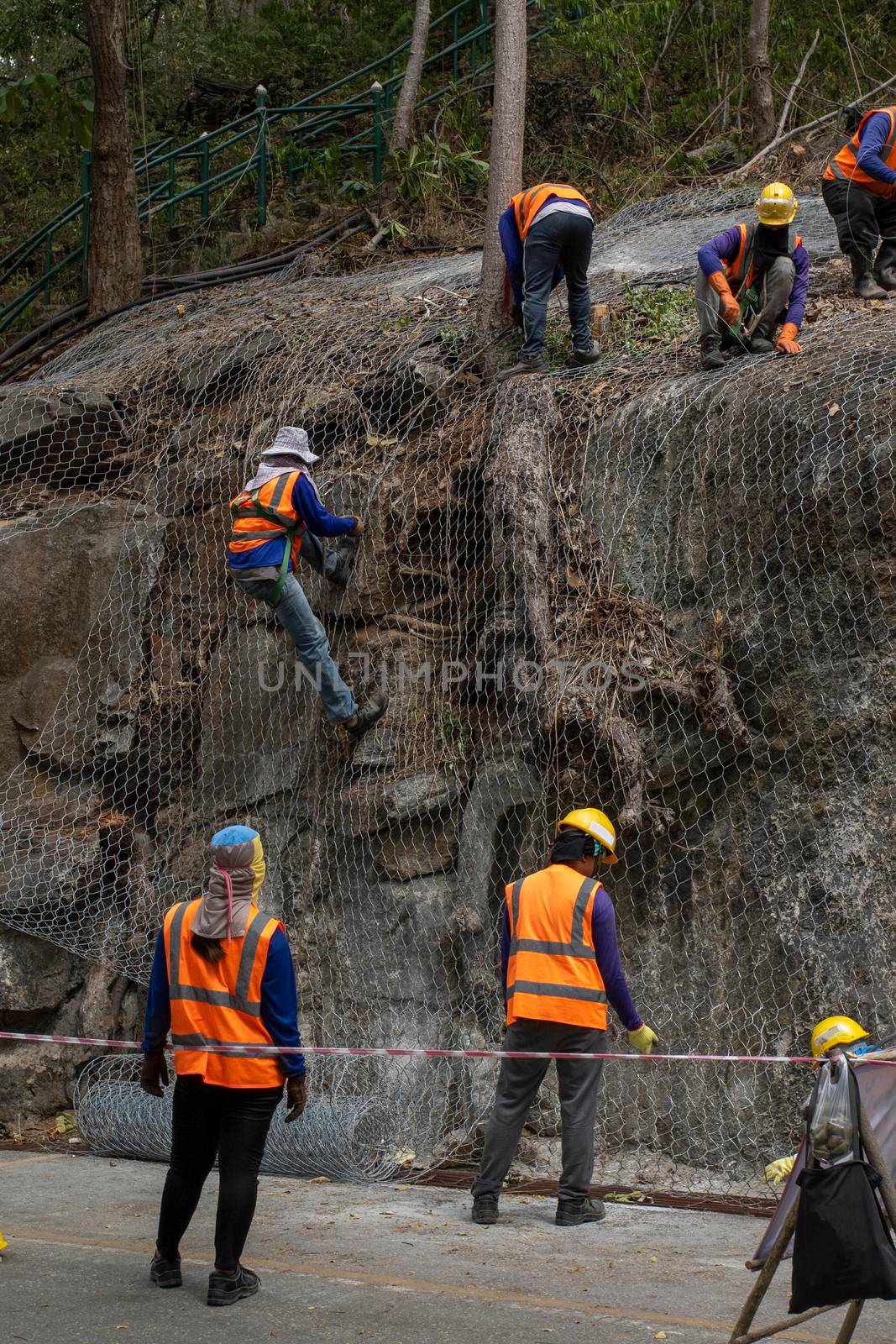 Construction workers are using the mesh to cover the large rocks on the side of the road. In order not to let the stone fall down.