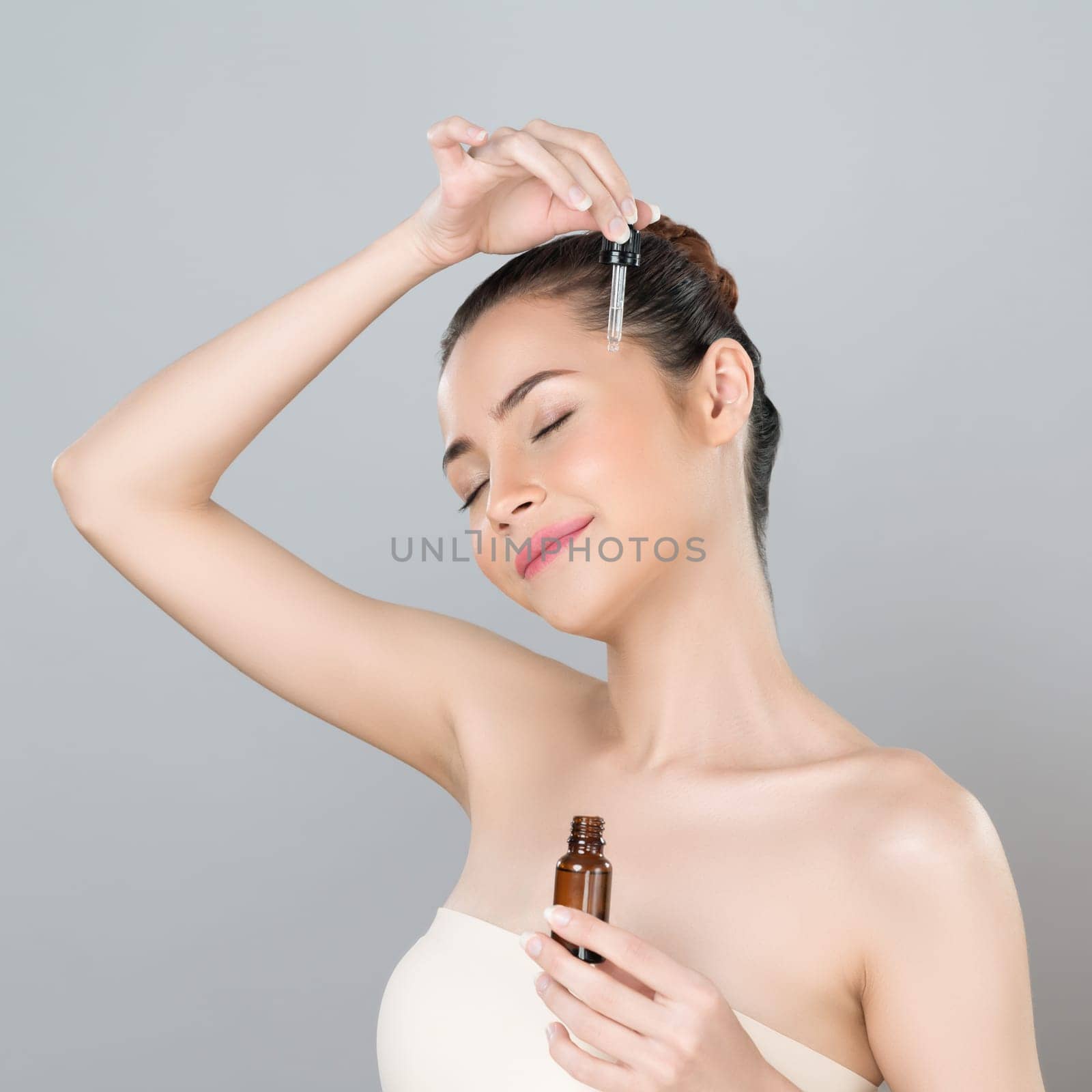 Glamorous portrait of beautiful woman applying extracted cannabis oil bottle for skincare product. CBD oil dropper pipette for cosmetology treatment and cannabinoids concept in isolated background.