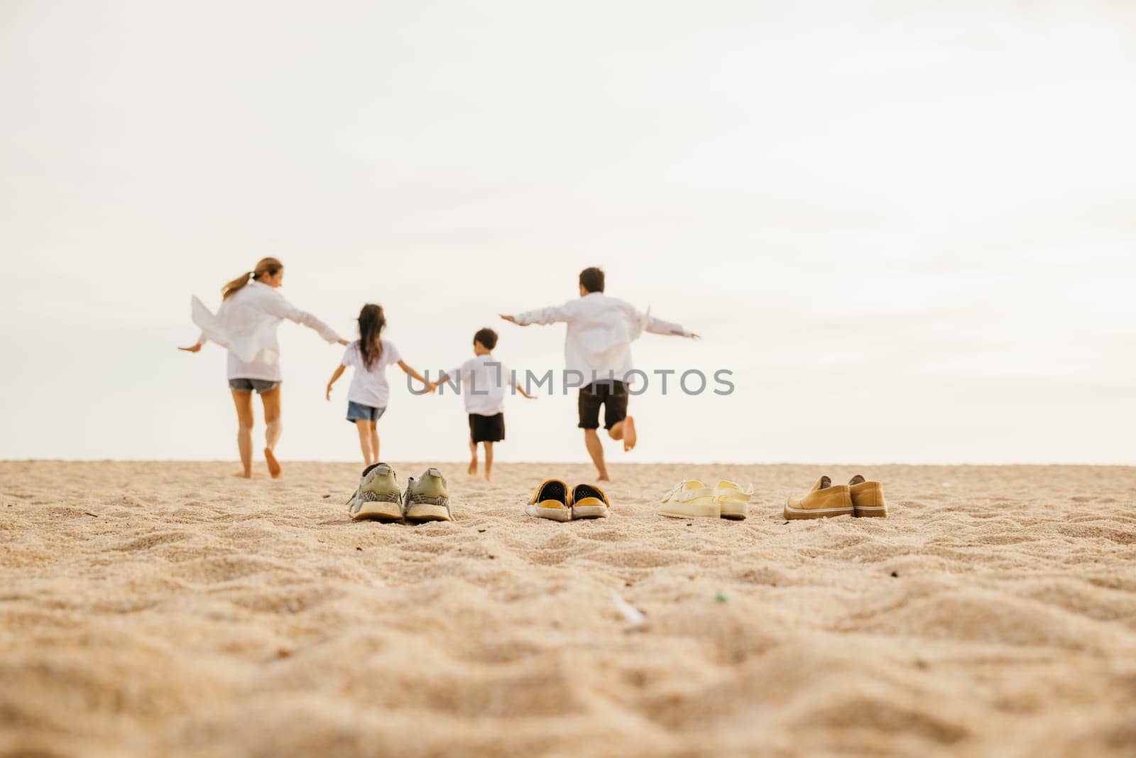 Back view of family parents with children enjoy fun holding hands together running to beach in holiday, Lifestyle dad, mom and kids take off shoes run on sand beach, Travel, active, Happy family day