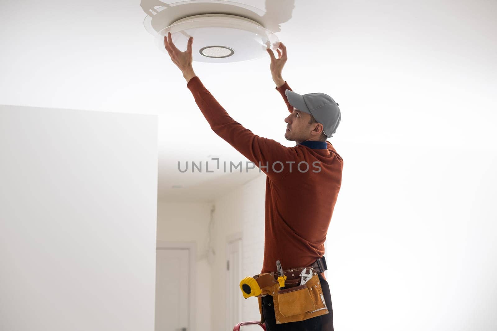 Electrician worker installation electric lamps light inside apartment. Construction decoration concept