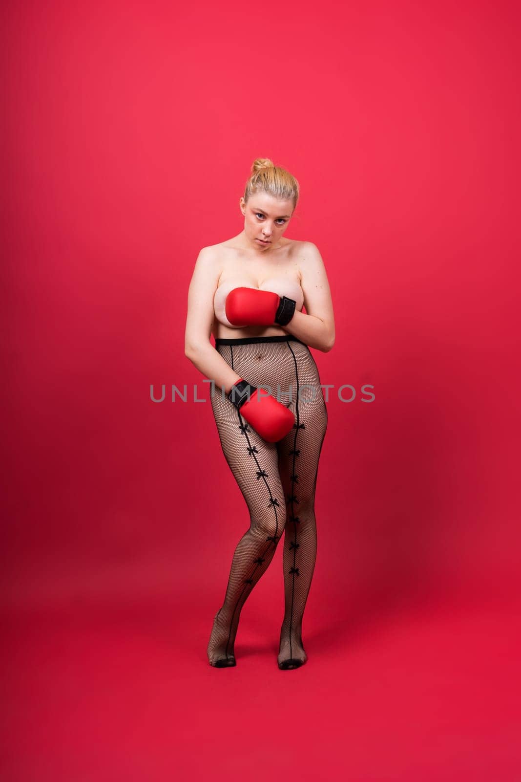 Seductive young and fit female fighter posing in gloves in a studio