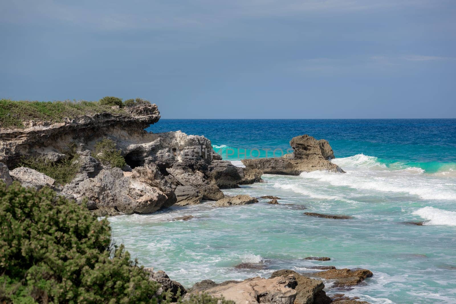 The coastline of the Caribbean Sea with white sand and rocks in Cancun.