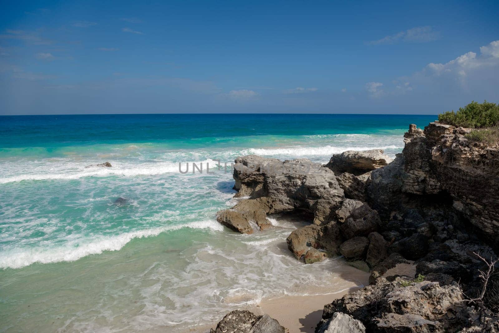 The coastline of the Caribbean Sea with white sand and rocks in Cancun.