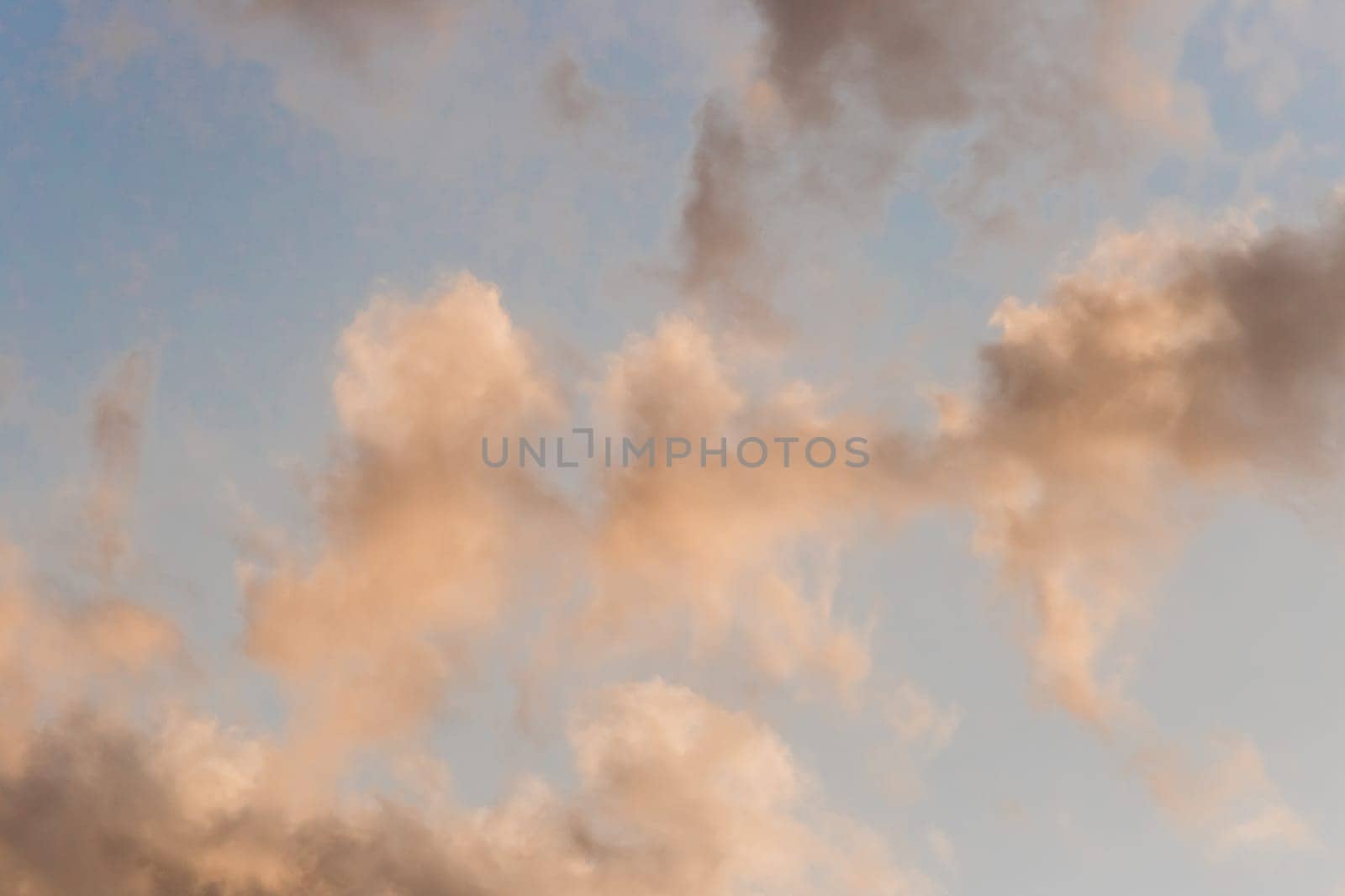 Soft airy warm yellow sunlight clouds sky blue evening natural background.