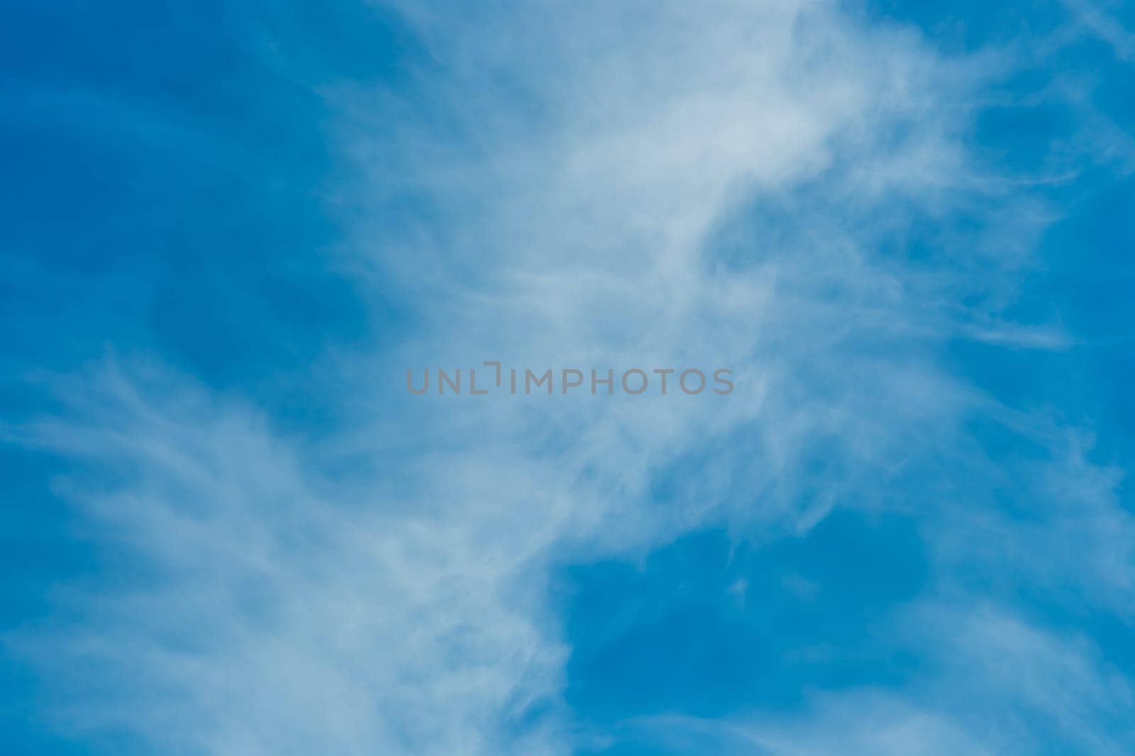 White cirrus clouds weather change wind natural background against the blue sky.