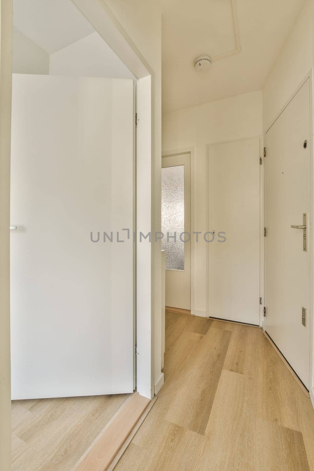 an empty room with white walls and wood flooring on the right side of the room, there is a door to the left