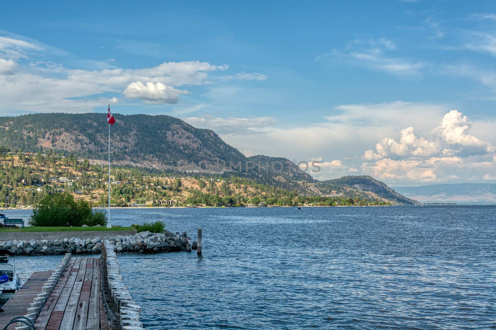 Okanagan lake overview on a bright summer day. Boat bay with canadian flag on the post