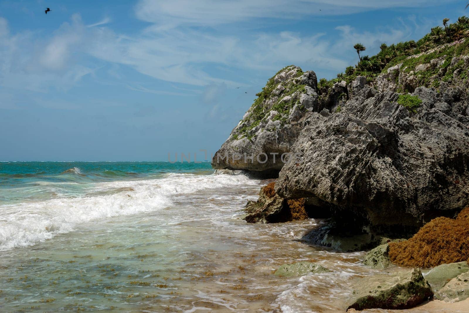 The coastline of the Caribbean Sea with white sand and rocks in Cancun.