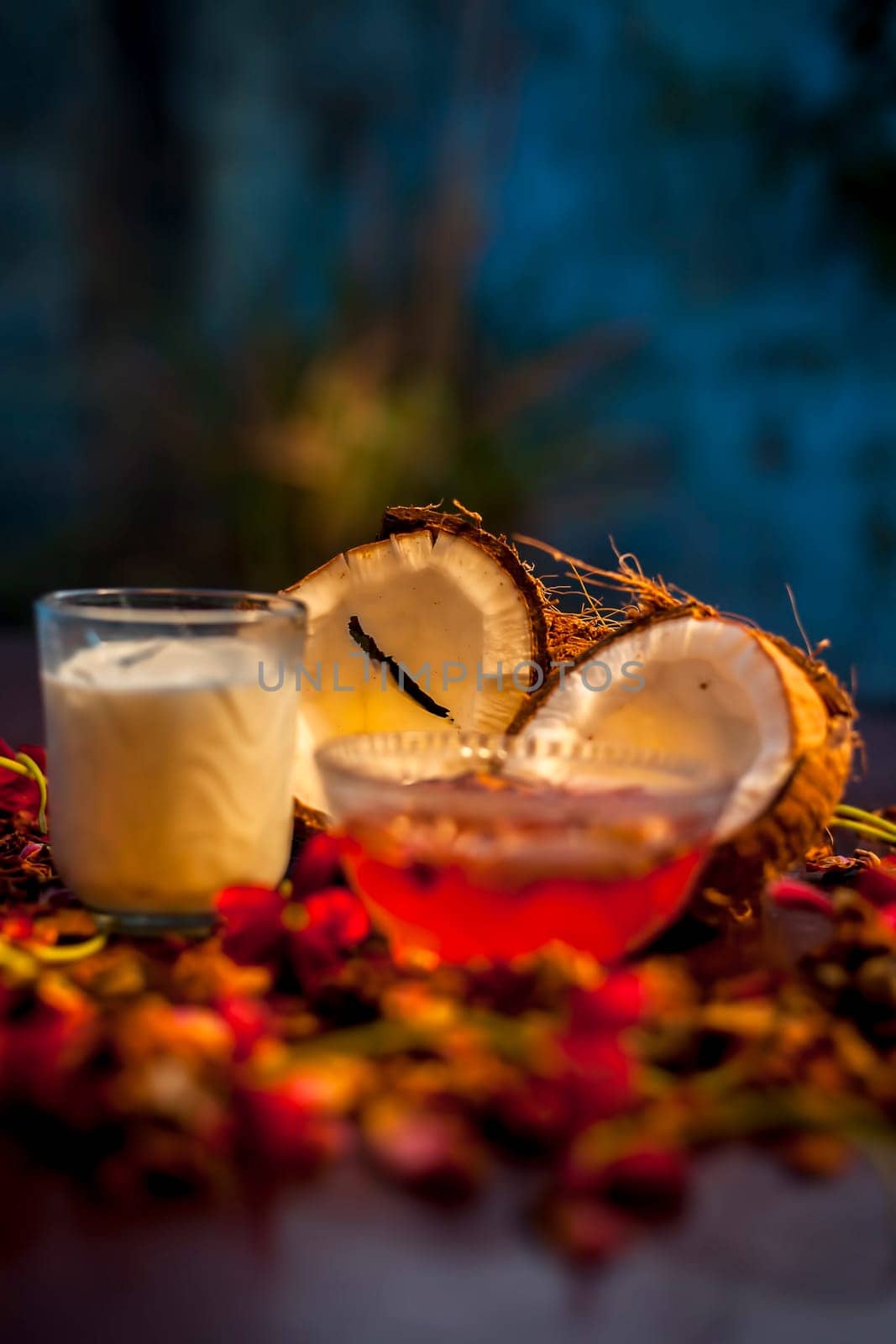 Coconut face mask consisting of coconut milk and yogurt for flawless skin and to moisturize it. Shot of raw coconut cut coconut, milk, and yogurt with some flowers spread on the brown wooden surface.