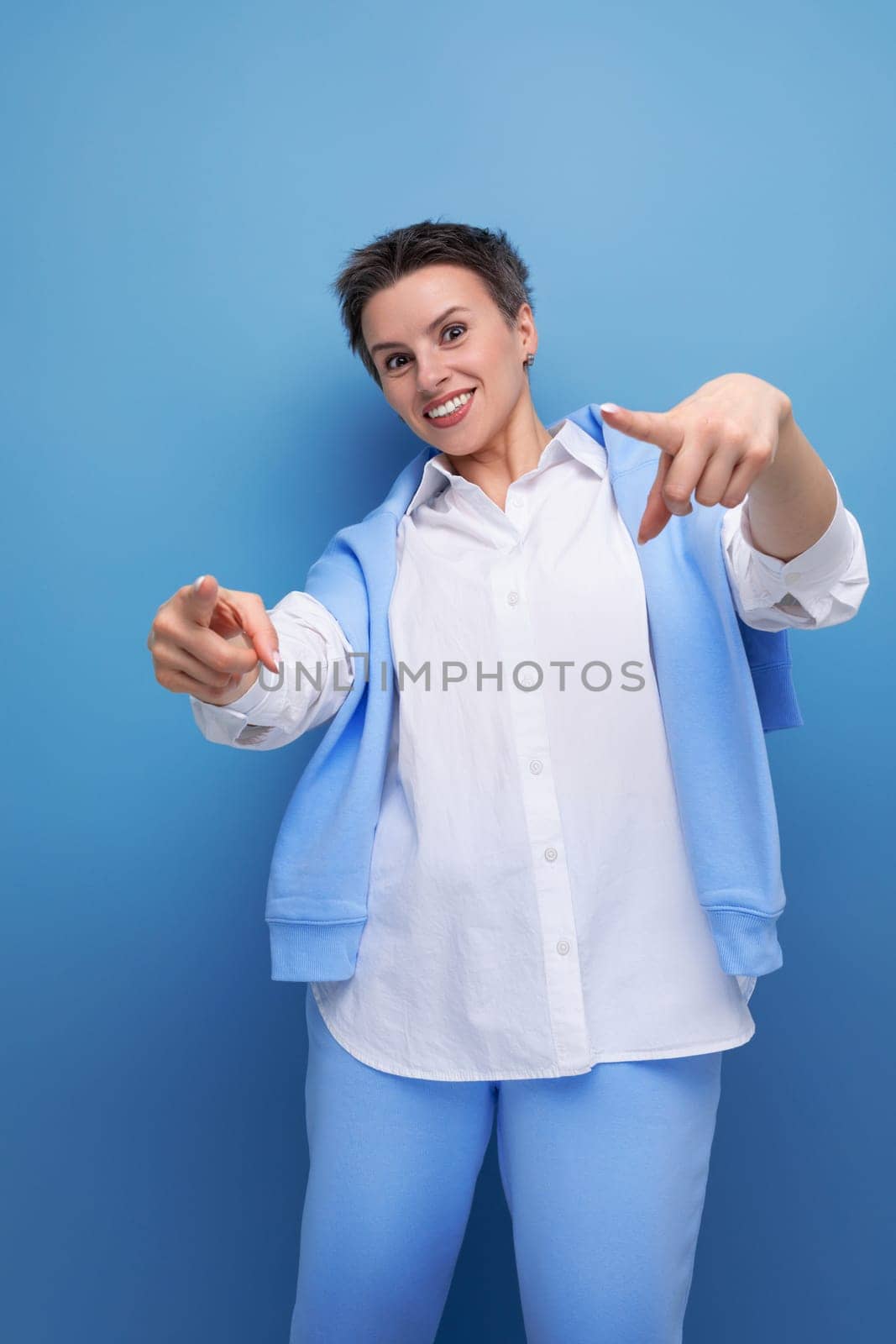 confident cool young lady with short haircut in white shirt on studio background.