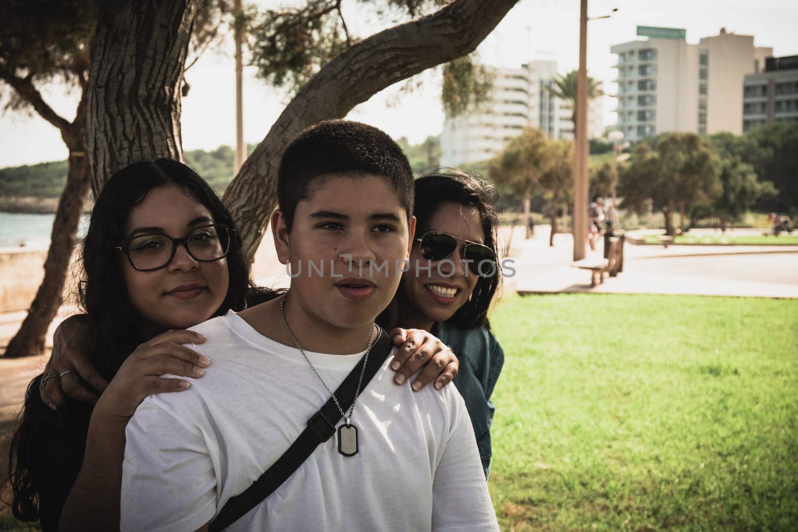 Cheerful group of young Latinos smiling at the camera in the open air, family portrait on a sunny day in the open air park.